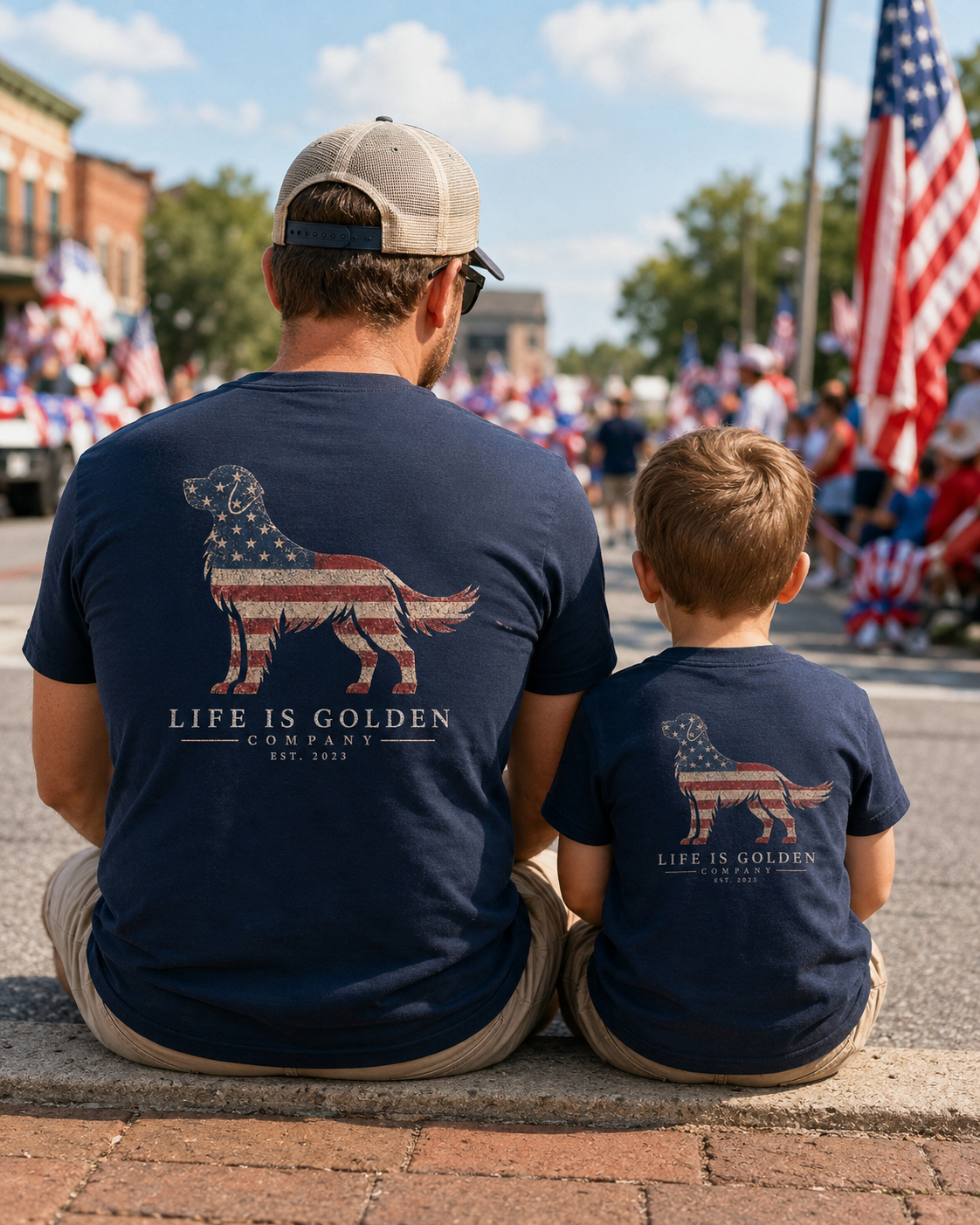 Stars & Stripes Golden Retriever Tee — lifestyle (father and son seated curbside at a 4th of July parade, both in navy tees)