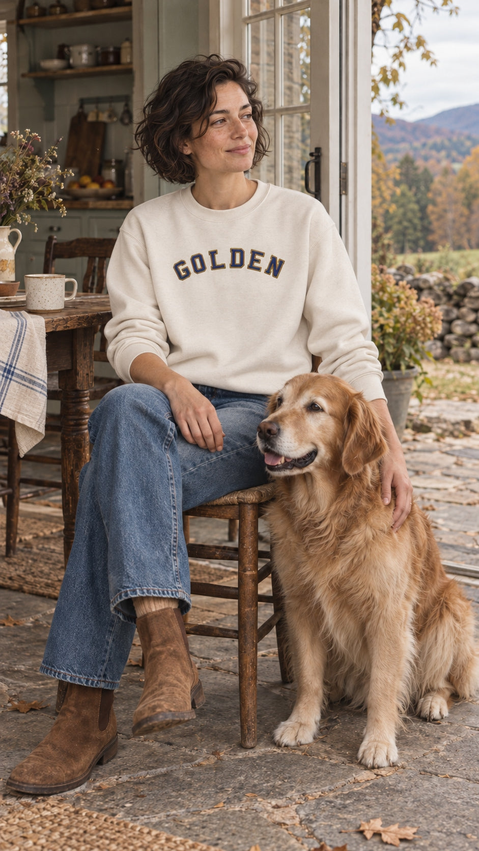 Woman wearing the Bone GOLDEN Varsity Relaxed Crew beside a golden at a Catskills farmhouse